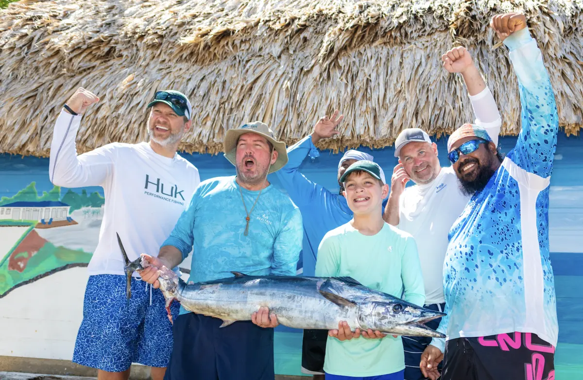Group of six men and a boy proudly posing with a large swordfish they caught.
